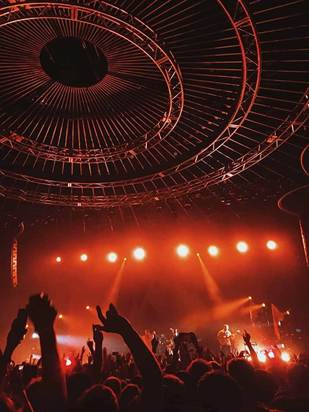 Photographie de mains dans les airs, à un concert, dans les tons rouge.