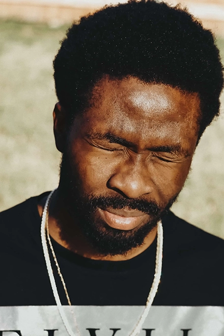 Portait d'un homme à la peau noire, fermant les yeux face au soleil.